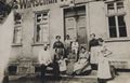 Familie und Bedienstete vor Wirtshausfassade